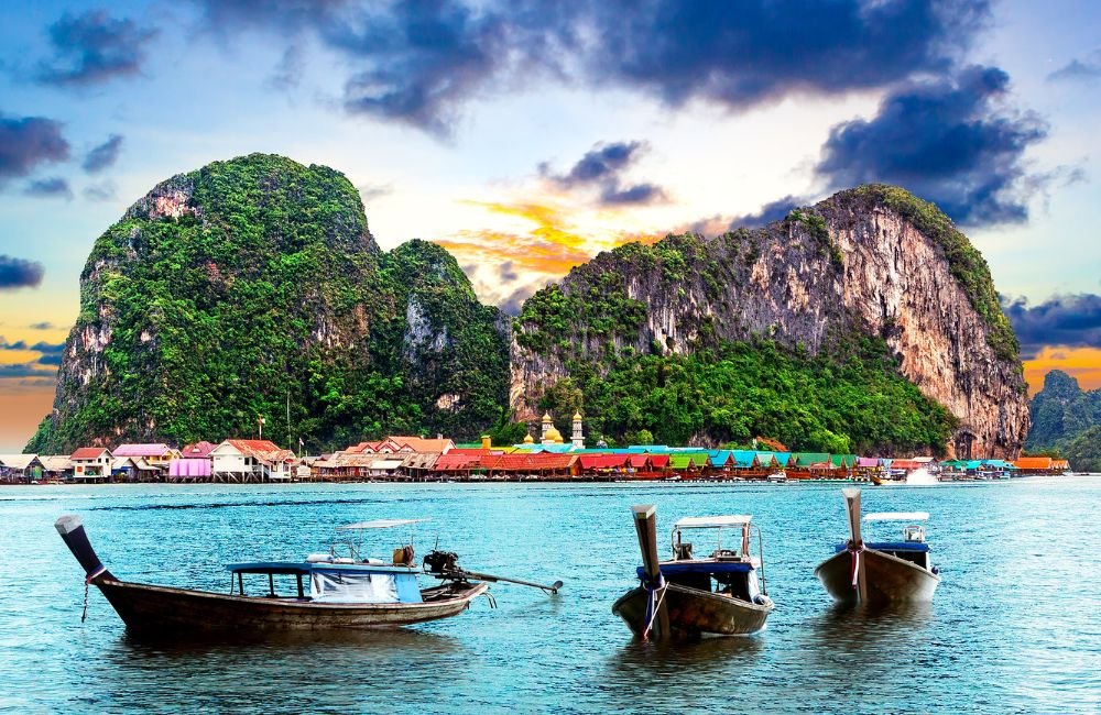Traditional Thai long-tail boats on a sandy beach at Railay, Krabi, with turquoise water and limestone cliffs.