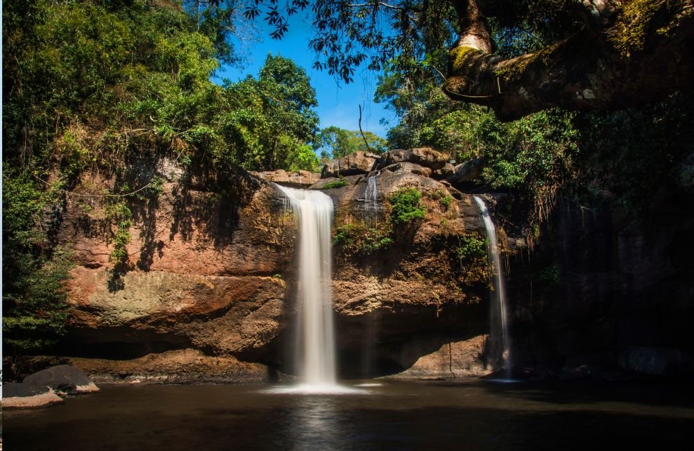 Haew Suwat Waterfall cascading over rocky cliffs into a natural pool surrounded by tropical forest in Khao Yai National Park, Thailand.